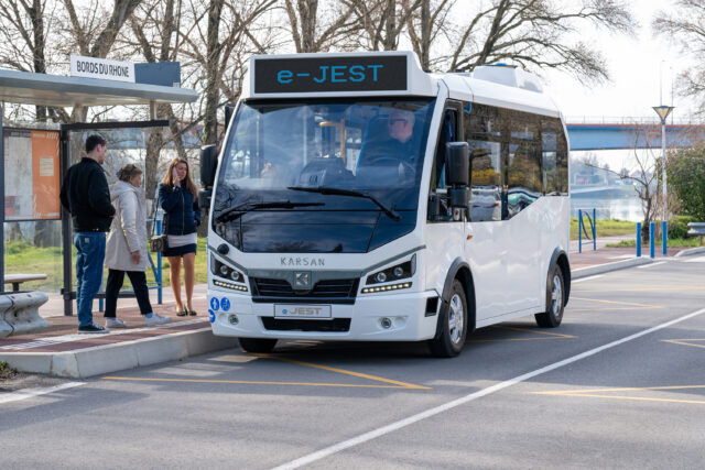 Personnes qui attendent à un arrêt une navette électrique.